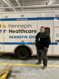 Commissioner Lunde wearing a mask next to a Hennepin Healthcare EMS van.