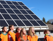 students smiling while standing in front of a solar array
