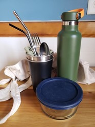 To go kit contents with reusable water bottle, cup, straw, utensils, container, and bag