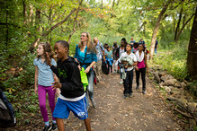 Kids and teacher hiking through forest