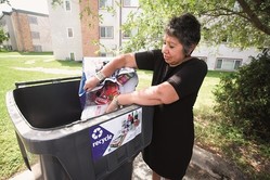 Woman putting recyclables into cart outside of apartment building