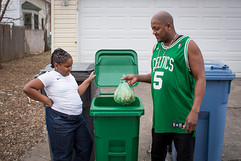 Man and young girl outside home putting organics bag into organics cart