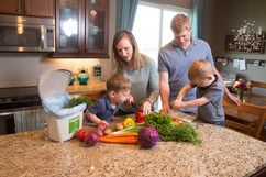 Mom and dad in kitchen with two young boys cutting up vegetables