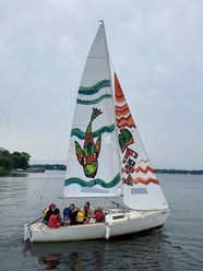 Group in sailboat with decorated aquatic invasive species art sail