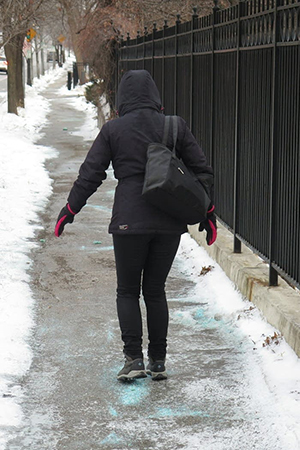 Woman walking on salt filled icy sidewalk