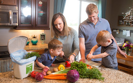Family in kitchen chopping vegetables