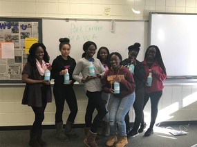 Group of girls with the Minnesota African Women's Association holding bottles of homemade green cleaners