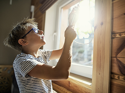 Young boy closing blinds