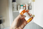 Person holding a bottle of prescription medication in front of a medicine cabinet