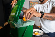 Man putting orange peel in organics bin