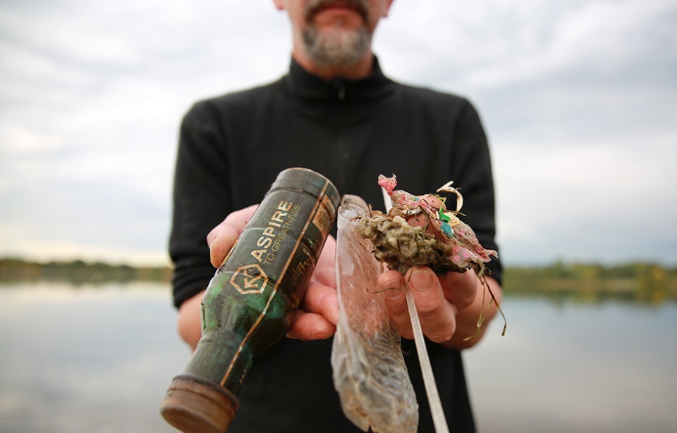 Man holding garbage near a lake