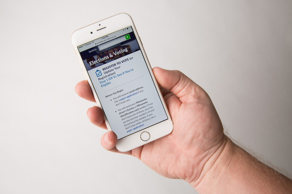hand holding a mobile phone displaying a register to vote page