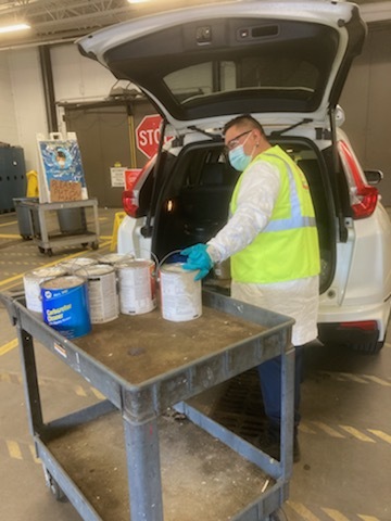 Staff unloading paint from vehicle at drop-off facility