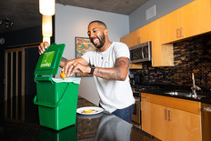 Man putting food into organics recycling countertop pail