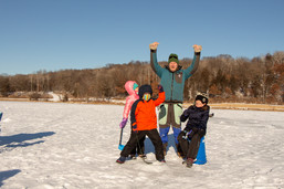 Dad and kids bundled up for winter celebrating on a frozen lake