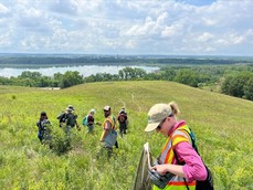 Hennepin County conservation specialists and partners harvesting seeds in a prairie overlooking the Minnesota River