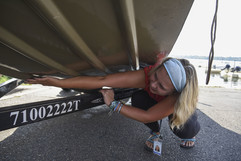 Woman looking at the underside of a boat on a trailer for possible aquatic invasive species