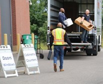 Three men loading used building materials into a box truck