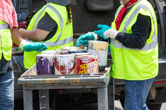 Workers in safety vests putting paint cans onto a cart