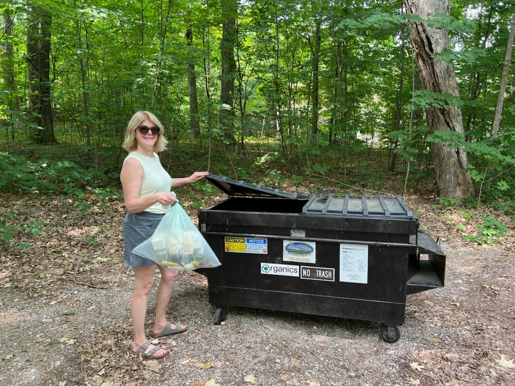 woman putting organics into a drop-off dumpster
