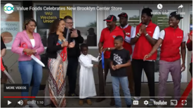 Group of people clap and hold large scissors after cutting ribbon at new Value Foods in Brooklyn Center