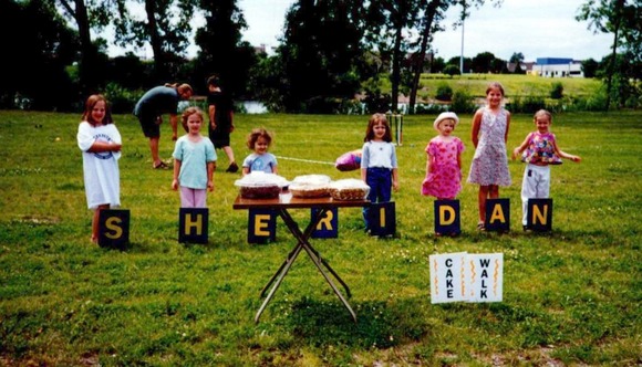 "Sheridan" spelled out in yard sign letters with children standing behind them at the Cake Walk
