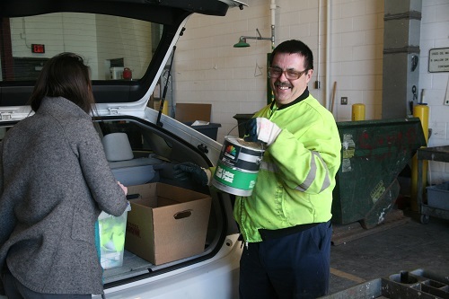 Woman and drop-off facility worker unloading paint from car