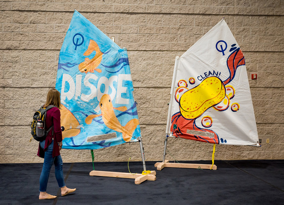 Person looking at AIS prevention art sails on display on stands. Sails say "clean" and "dispose"