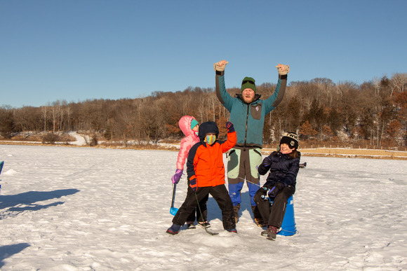 Dad and kids on lake in winter with hands in the air celebrating