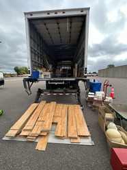 Used wood flooring laying on the ground by a box truck at a used building material collection event