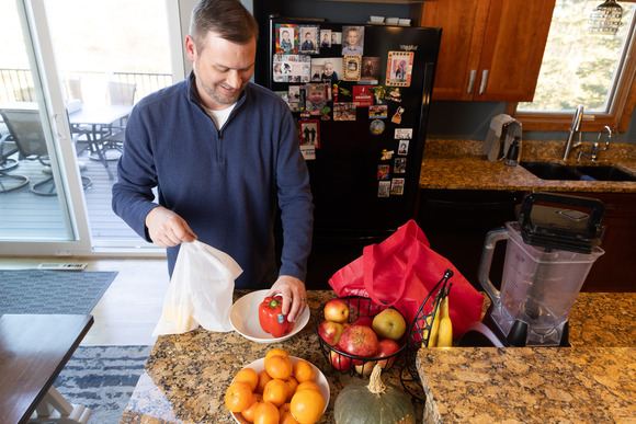 Man in kitchen with reusable bags packing up fruit and vegetables