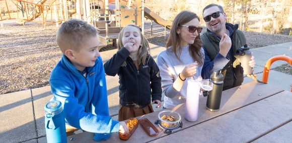 Family eating out of plastic bins in park to support single use plastic reduction