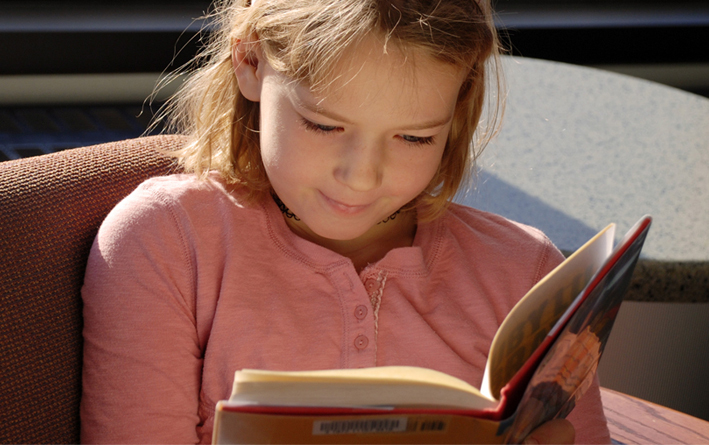 child smiling while reading book