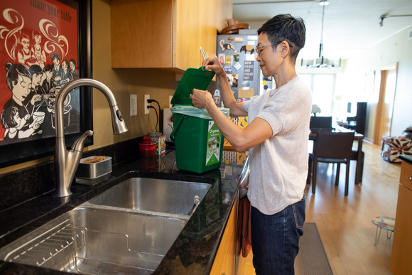 Woman putting food scraps into a countertop organics recycling container