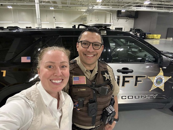 Heather smiles in a selfie with Deputy Saenz in front of a Hennepin County Sheriff's Office vehicle.