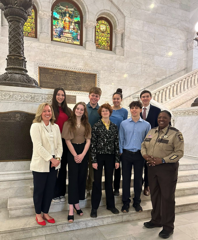 Heather poses with her Intern for a Day cohort (7 students) and Sheriff Dawanna Witt in Minneapolis City Hall.