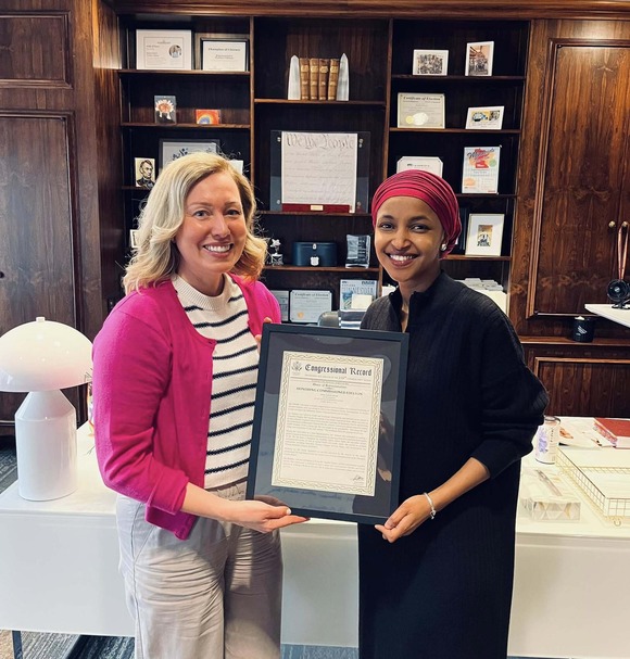 Heather smiles next to Congresswoman Ilhan Omar; they both hold the Congressional Record presented to Heather to honor her public service.