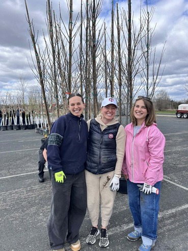 Heather poses with two staffers in front of trees that they helped unload.