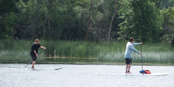 Two people on stand-up paddle boards on a lake
