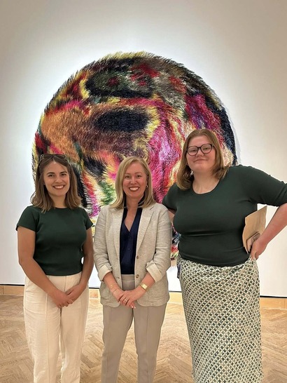 Heather stands smiling next to two staffers at the Mia's "Giants" exhibition.
