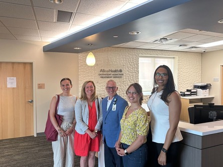 Heather poses with staff and Allina Health team members in the lobby of the Allina Mental Health and Addiction Center.