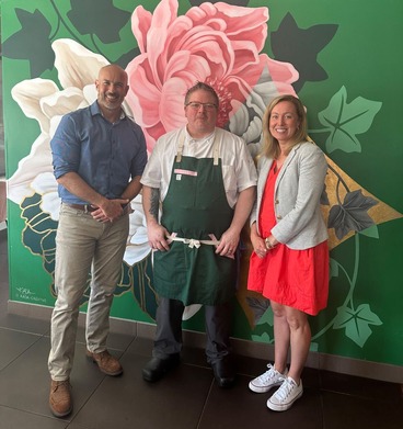 Heather smiles and poses with Hopkins Mayor Patrick Hanlon and a restaurant employee in the lobby of Pink Ivy Restaurant.