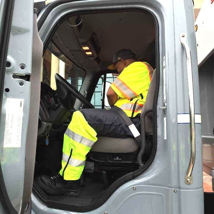 garbage hauler in truck wearing reflective suit