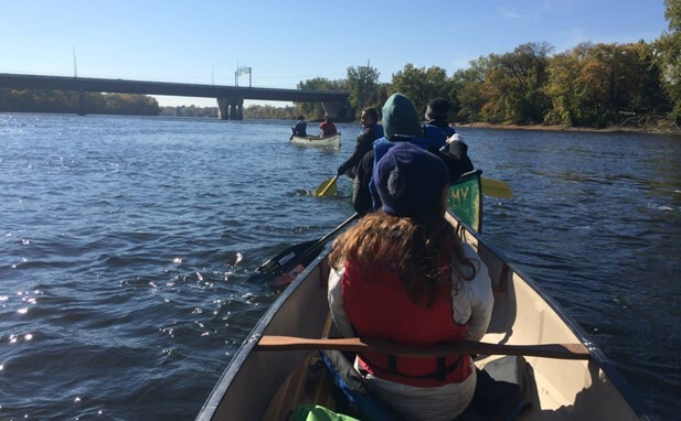 A group of canoes and paddlers on the Mississippi river.
