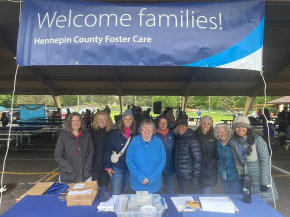 A group of staff smiling and welcoming families to a picnic celebrating foster care.