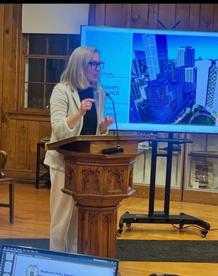 Heather speaks at a podium at the Deephaven City Council meeting.