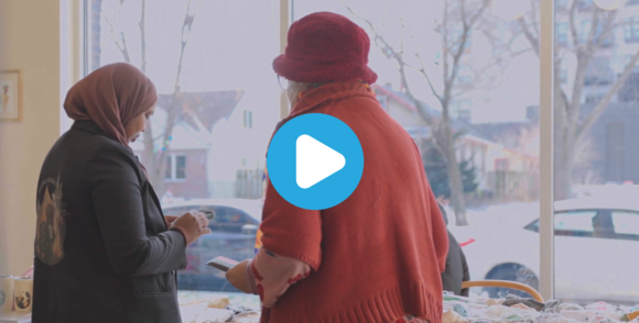 Screenshot of a video where two women are browsing children's clothing on a table