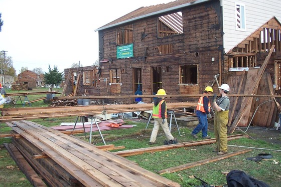 Workers reclaiming wood from a house