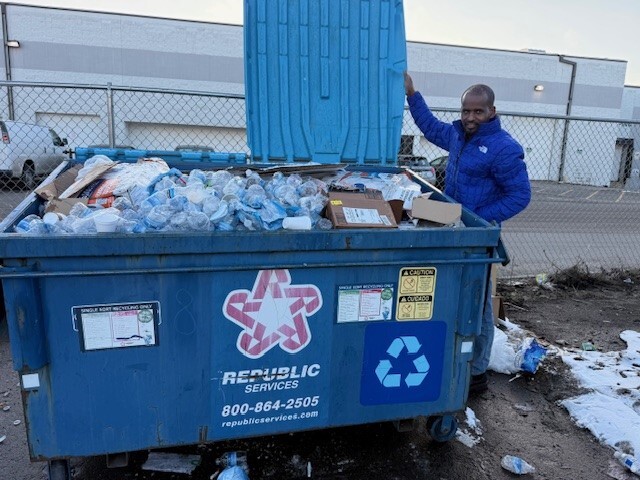 Eticha, CEO of Oromo Diaspora Media, showing an overflowing recycling dumpster during Ramadan.