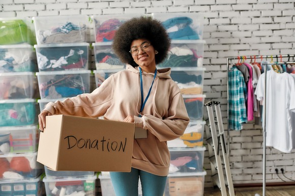 Person smiling, holding a box that says donations